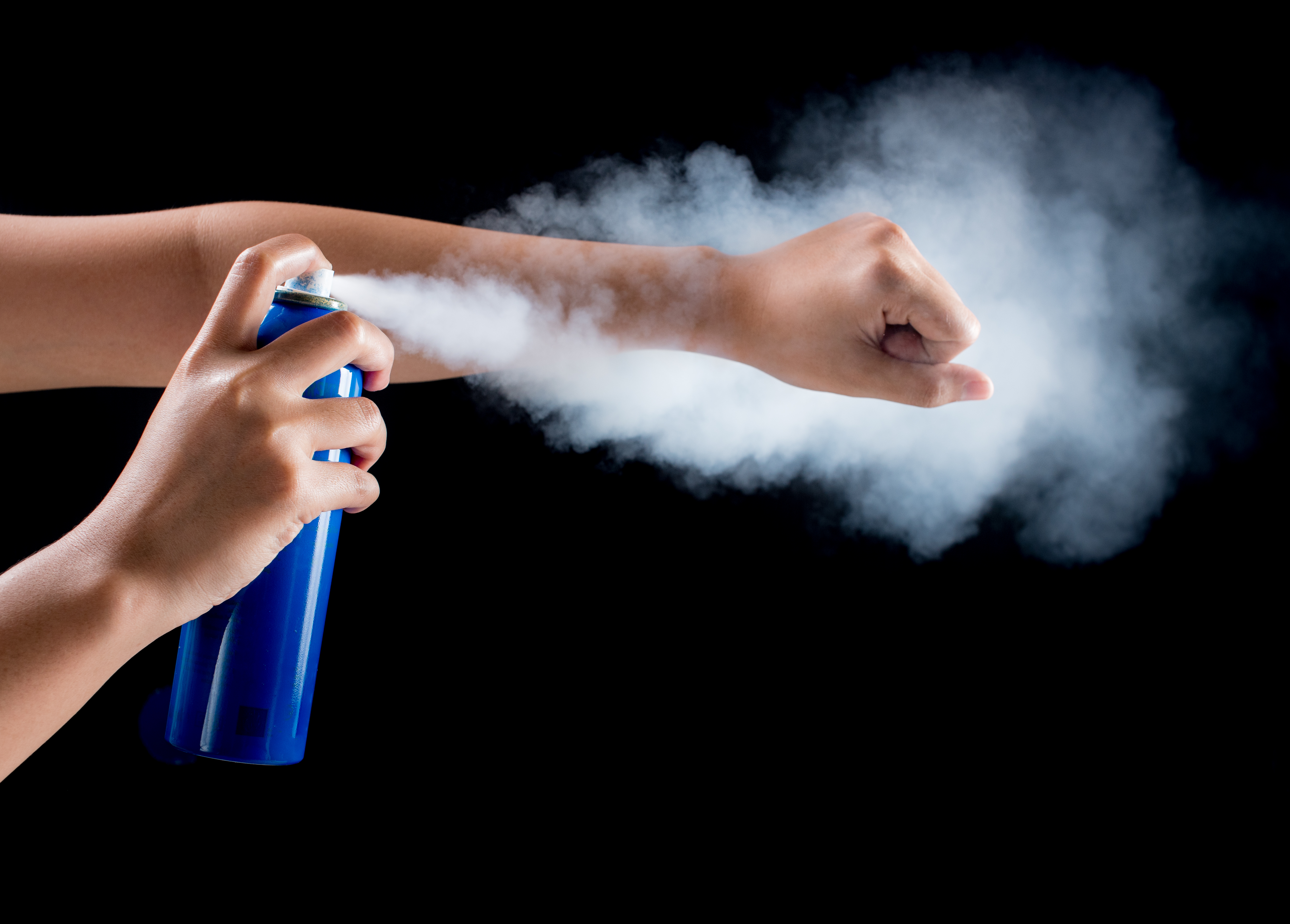 close-up-hand-spraying-while-holding-bottle-black-background